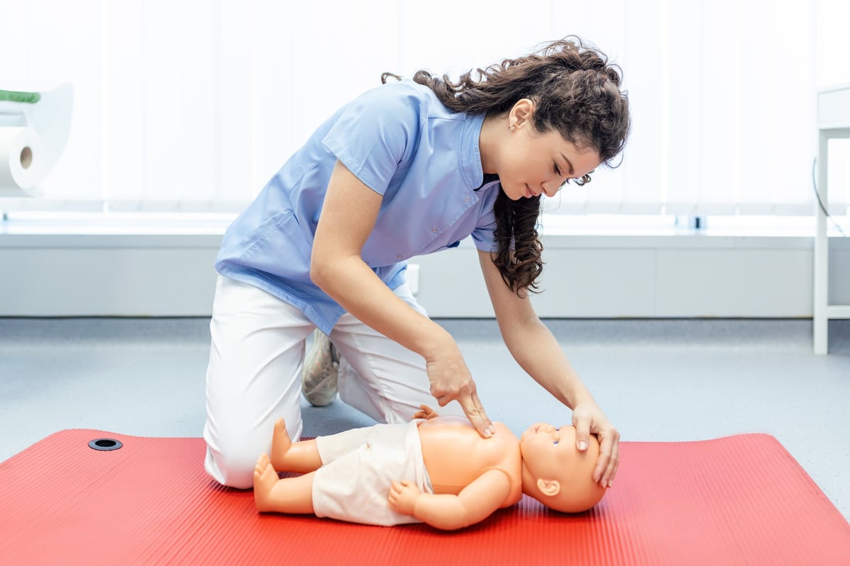 Mujer practicando RCP en un maniquí de bebé durante un curso de primeros auxilios
