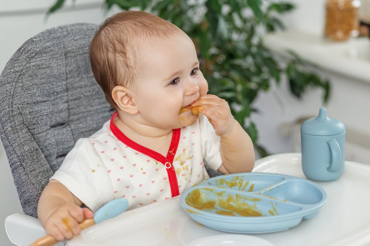 Bebé en su trona comenzando a comer papillas de forma autónoma